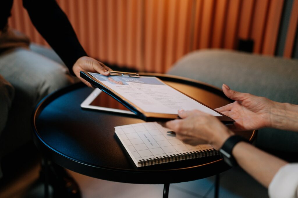 Two people are holding a tablet and papers.
